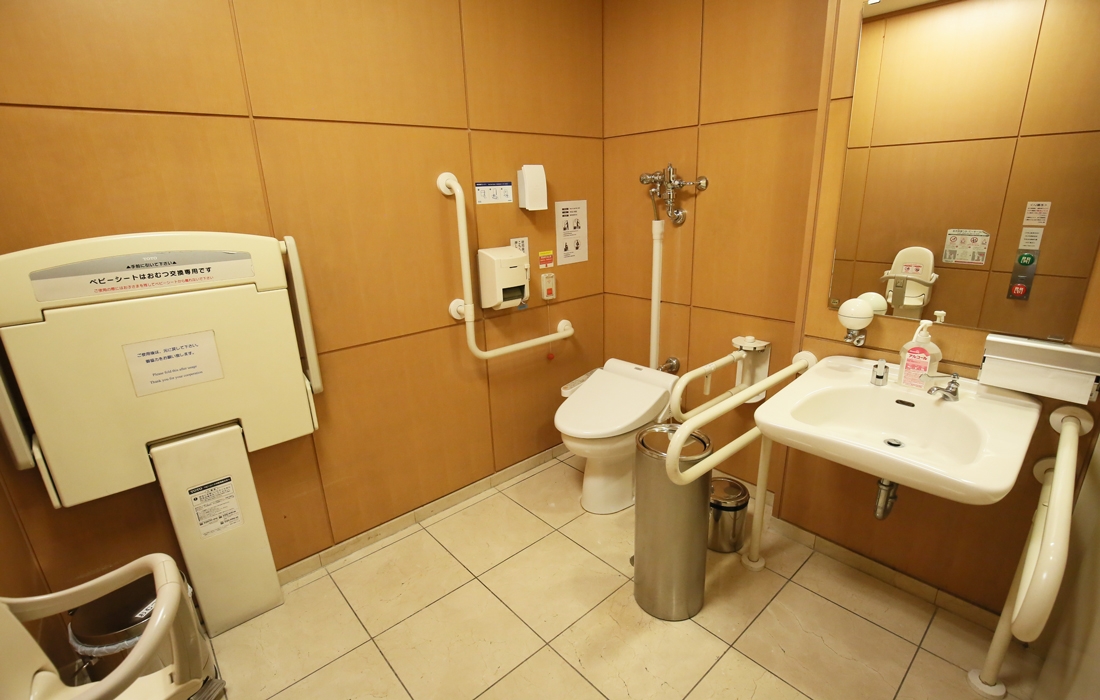 バリアフリーのトイレです。手すりが設置されたトイレと洗面台があり、ベビーシートも備わっています。